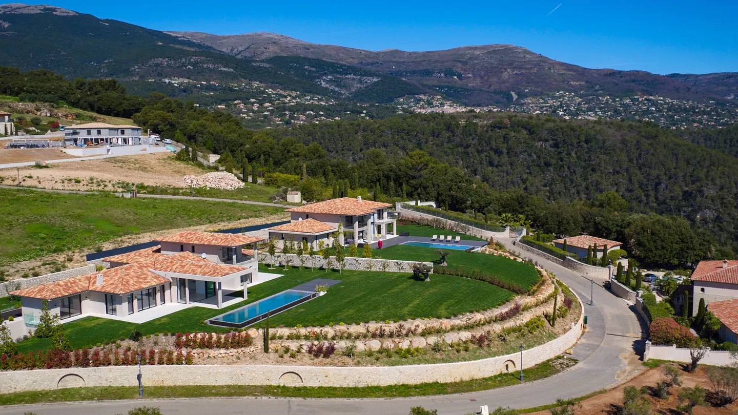 Aerial view of the property and its curved garden, with mountains behind