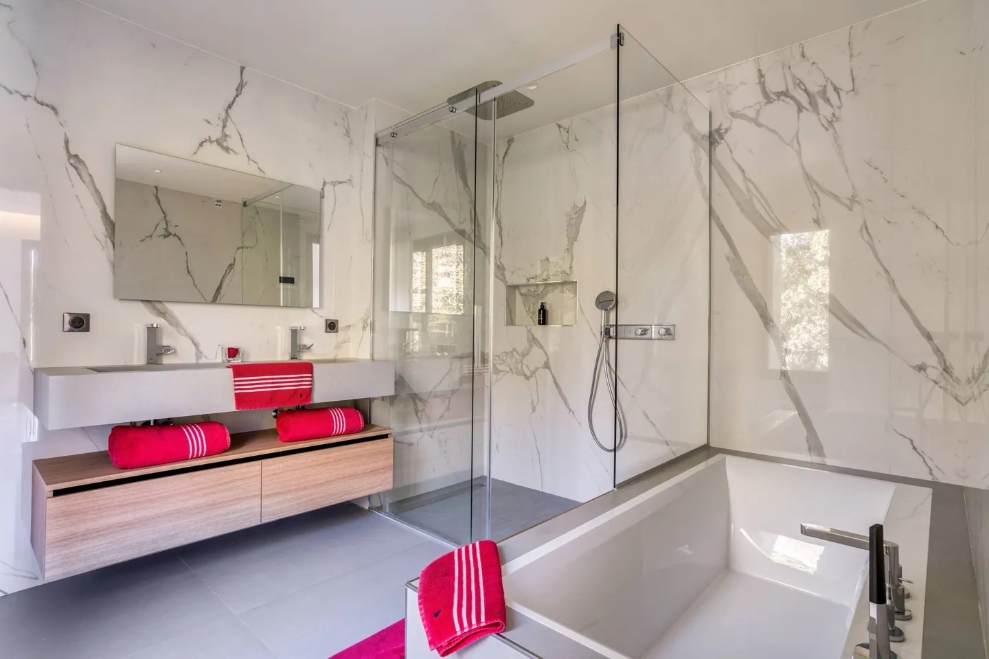 Salle de bains en marbre blanc veiné avec douche à l'italienne, baignoire et double vasque