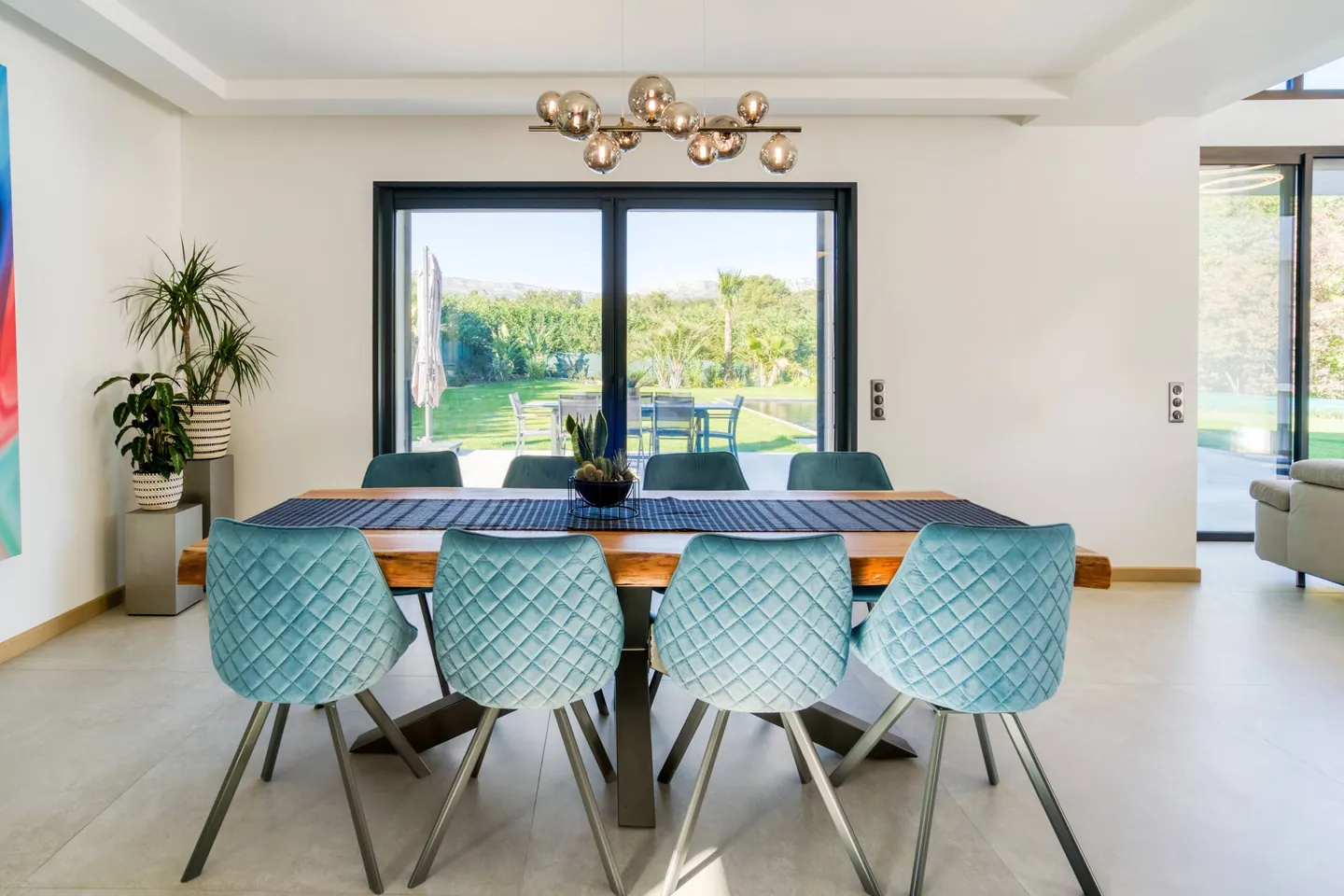 Salle à manger face à une baie vitrée donnant sur le jardin, suspension à globes en verre