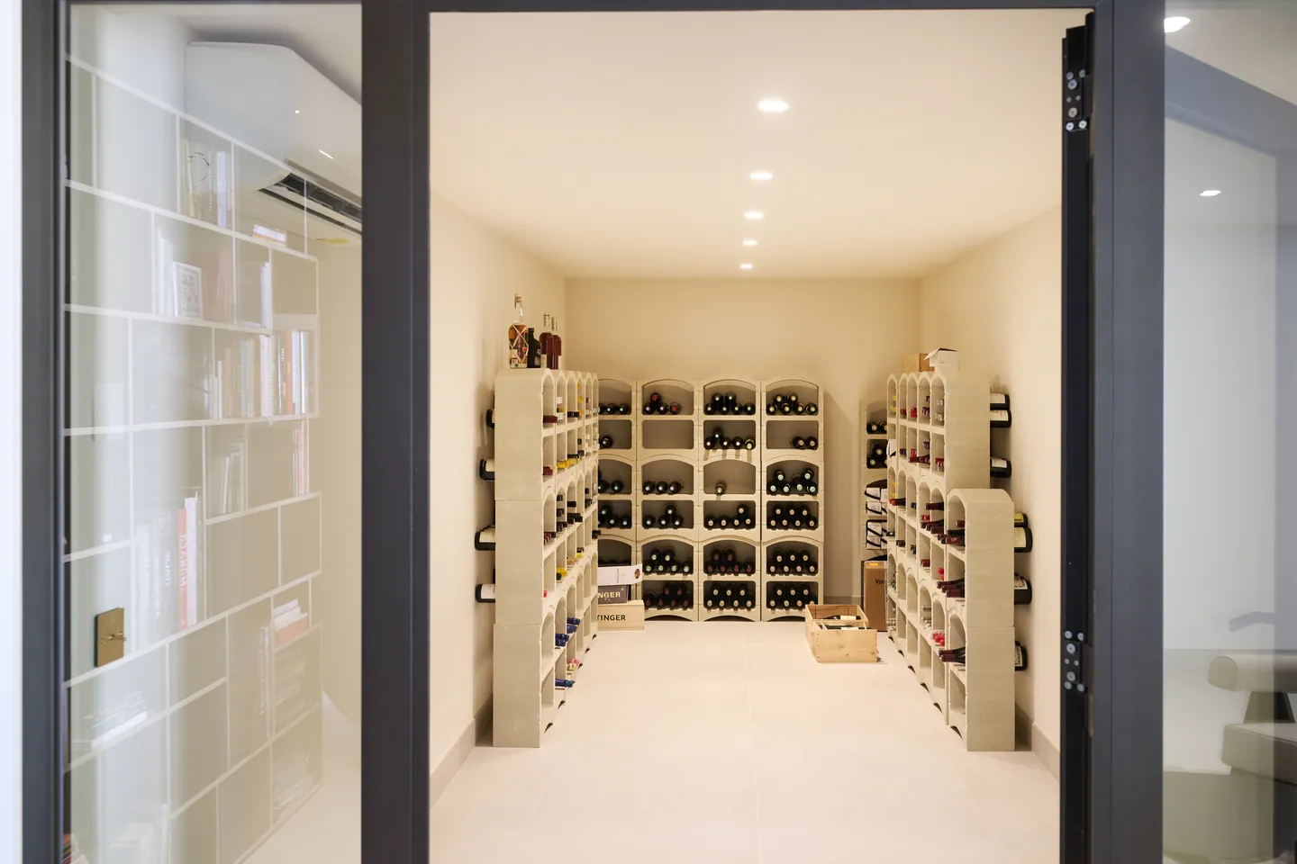 Cave à vin climatisée aux casiers modulaires, vue par la porte vitrée