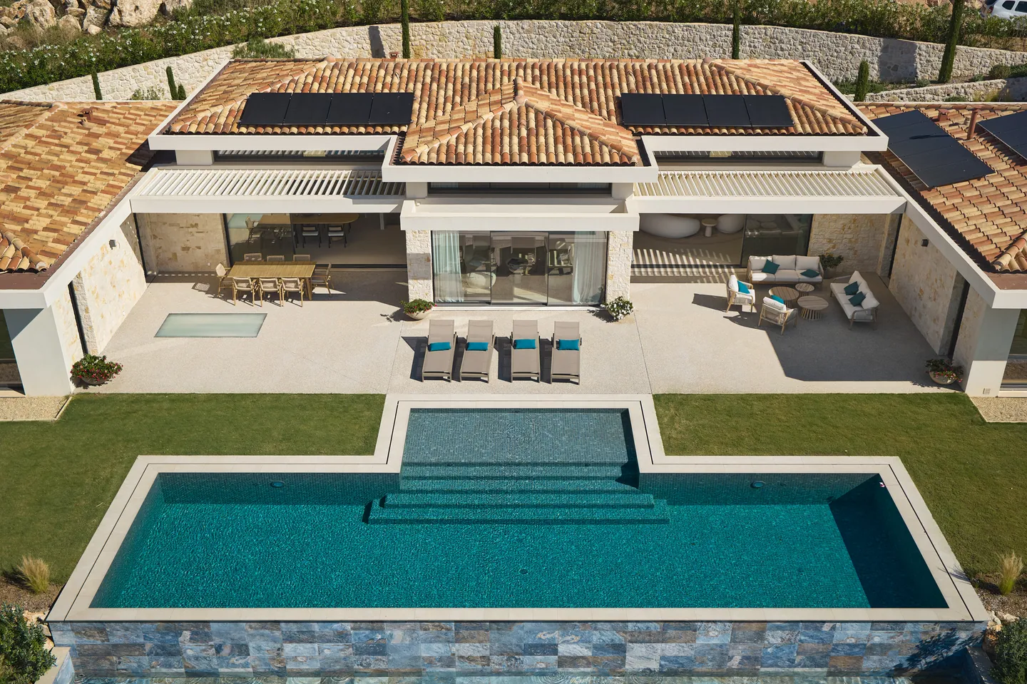 Vue plongeante sur la piscine à marches et la terrasse couverte de pergolas bioclimatiques