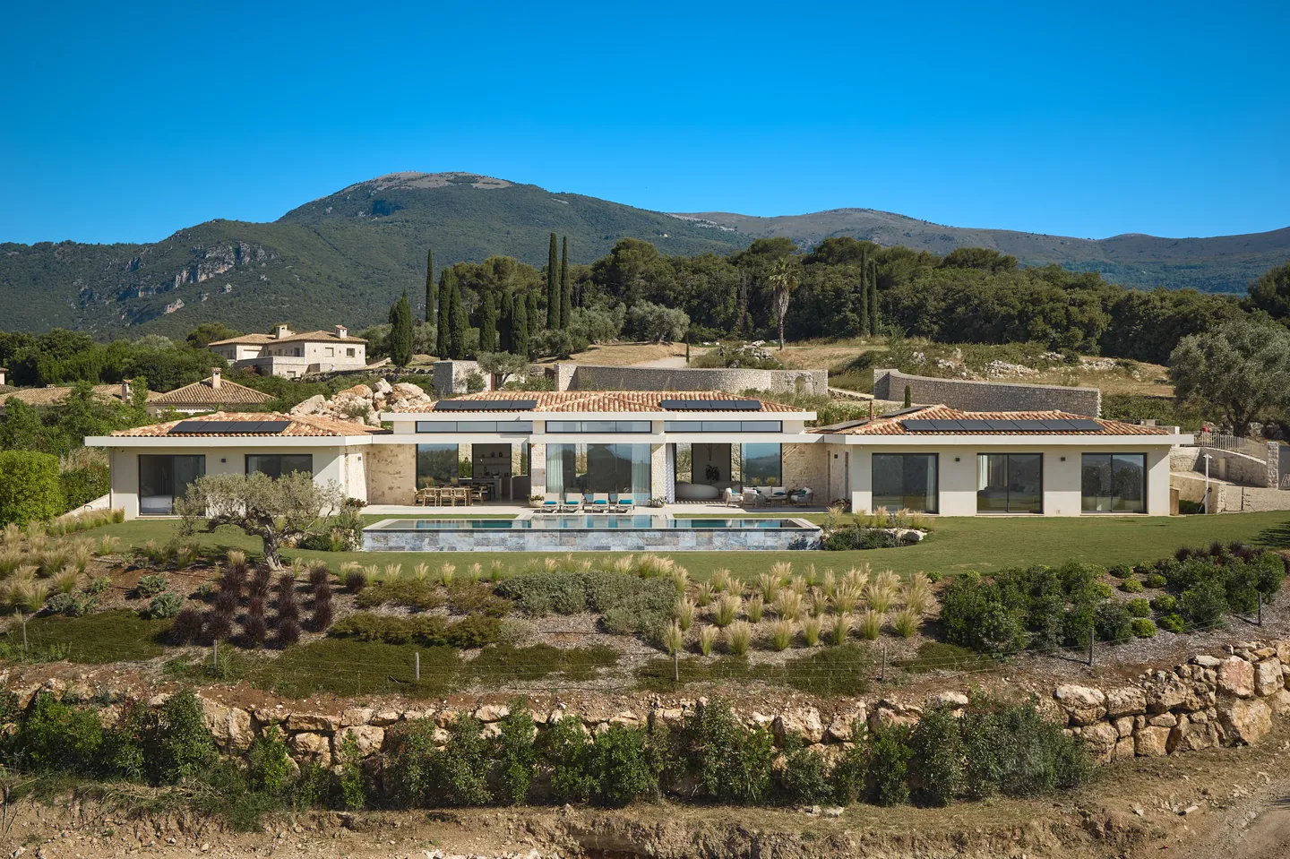 Villa de plain-pied aux toits de tuiles, piscine et jardin en restanques face aux collines boisées