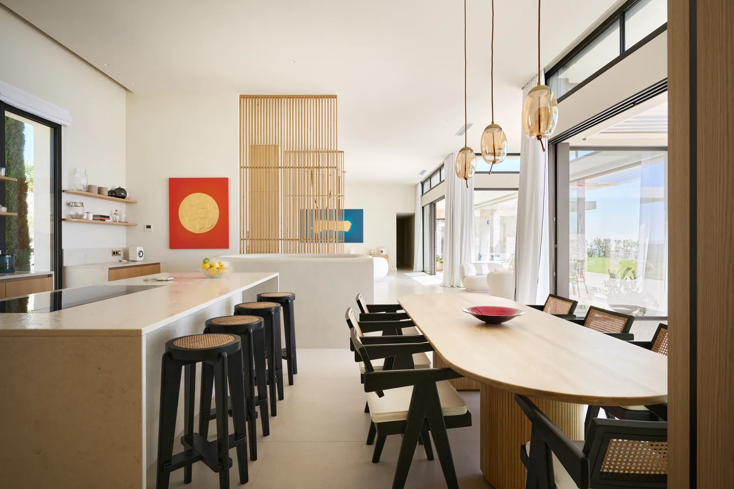 Îlot de cuisine en pierre avec tabourets cannés, table ovale et séjour ouvert en enfilade