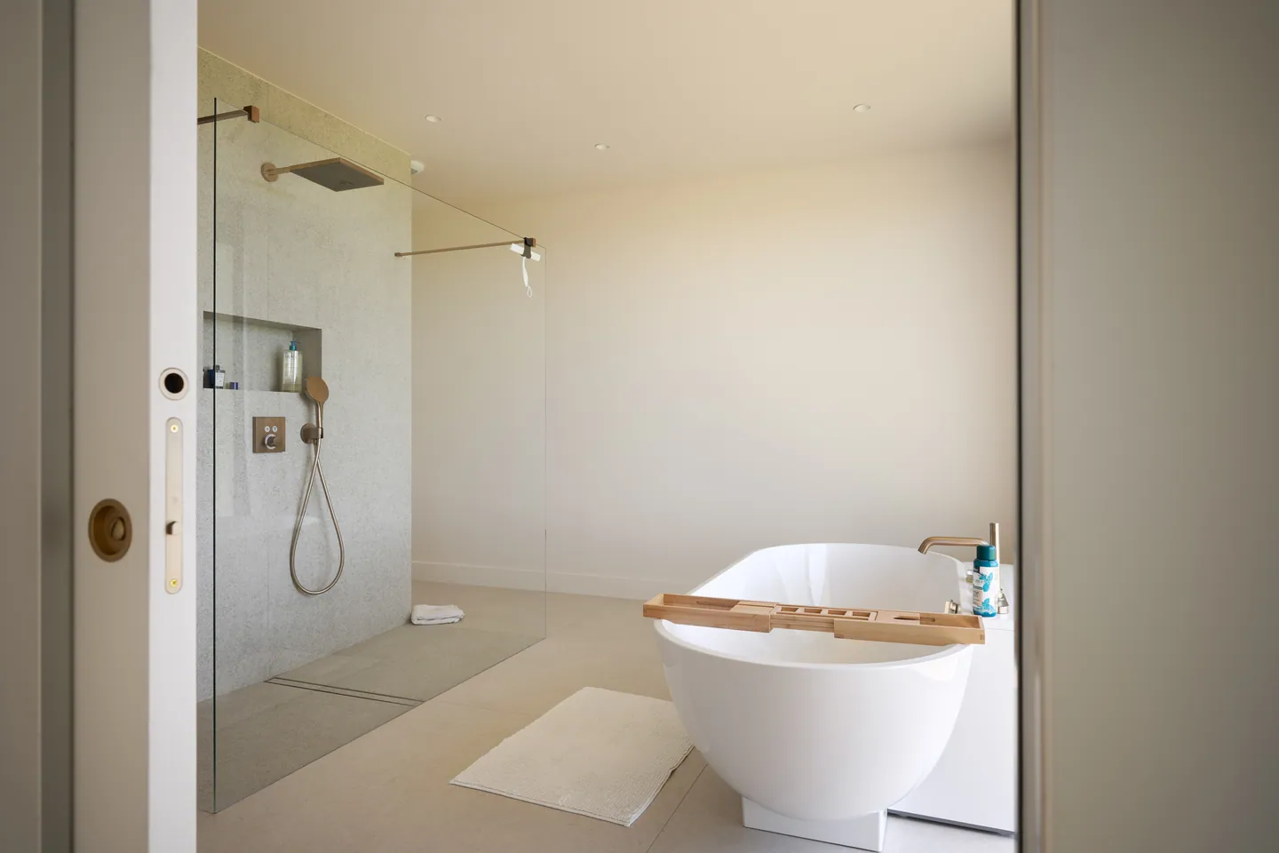 Salle de bains avec baignoire îlot et douche à l'italienne, vue par la porte coulissante