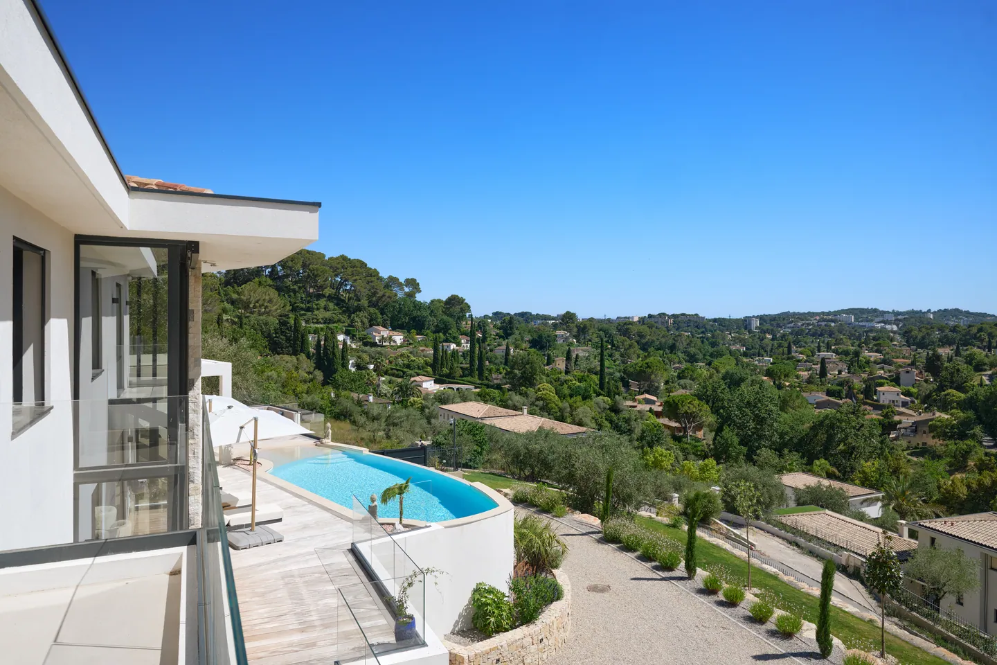 Vue depuis l'étage sur la piscine courbe, l'allée et les collines verdoyantes