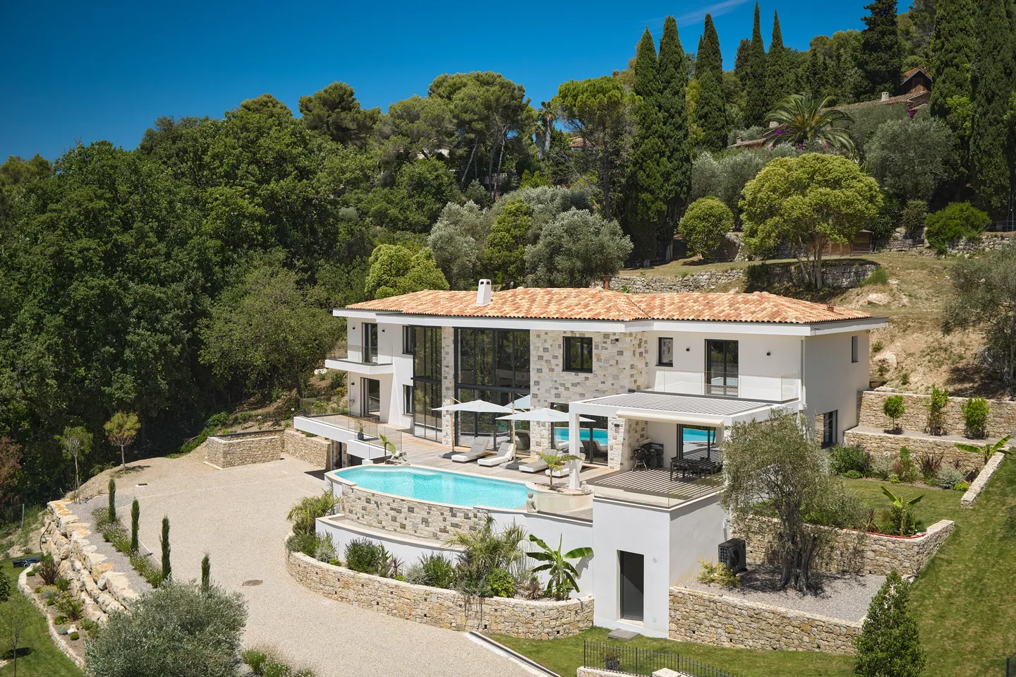 Vue aérienne de la villa, de sa piscine et de l'allée gravillonnée bordée de murets en pierre sèche