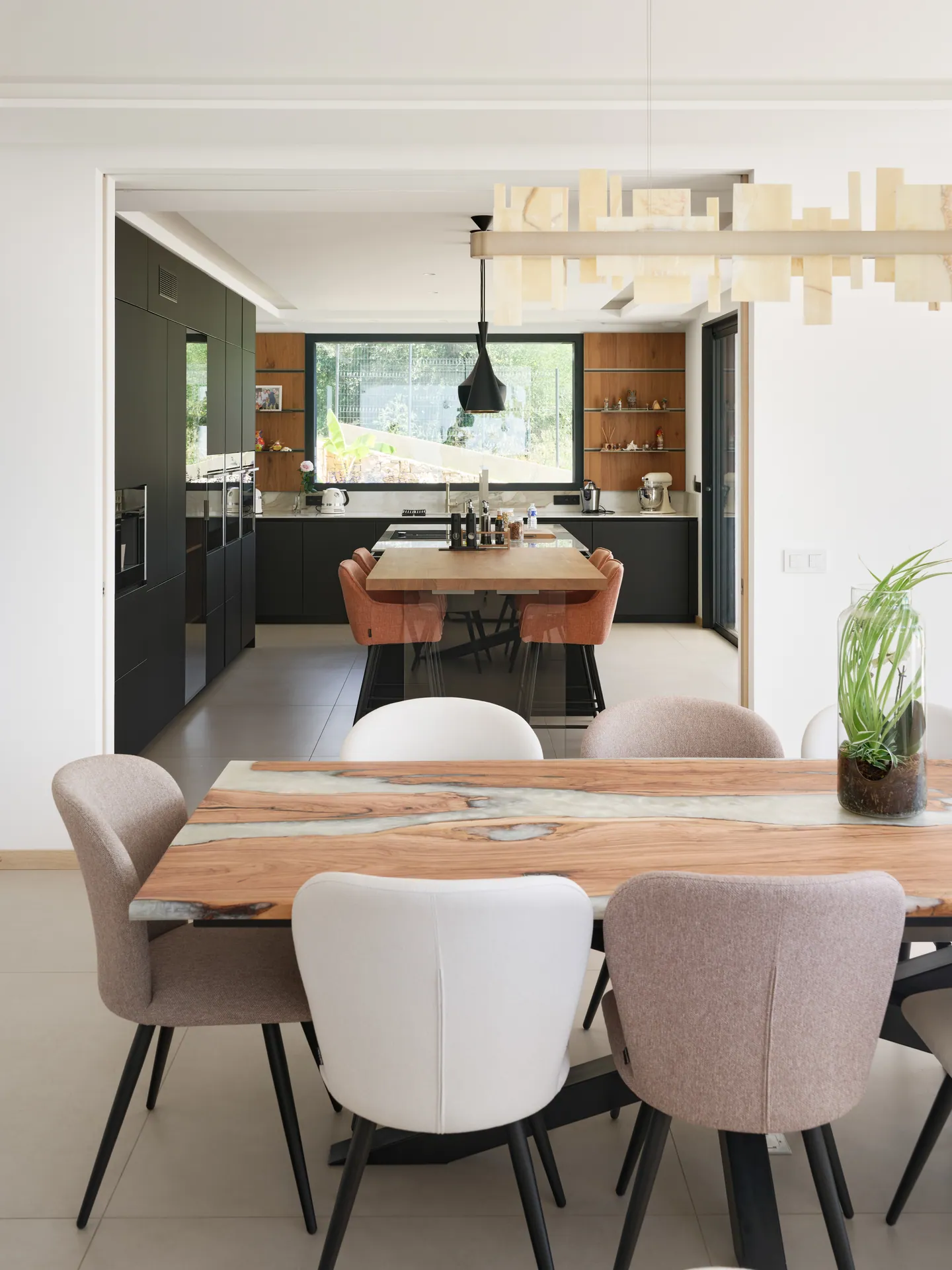 Table à manger en bois massif et chaises tapissées, cuisine noire et bois en enfilade