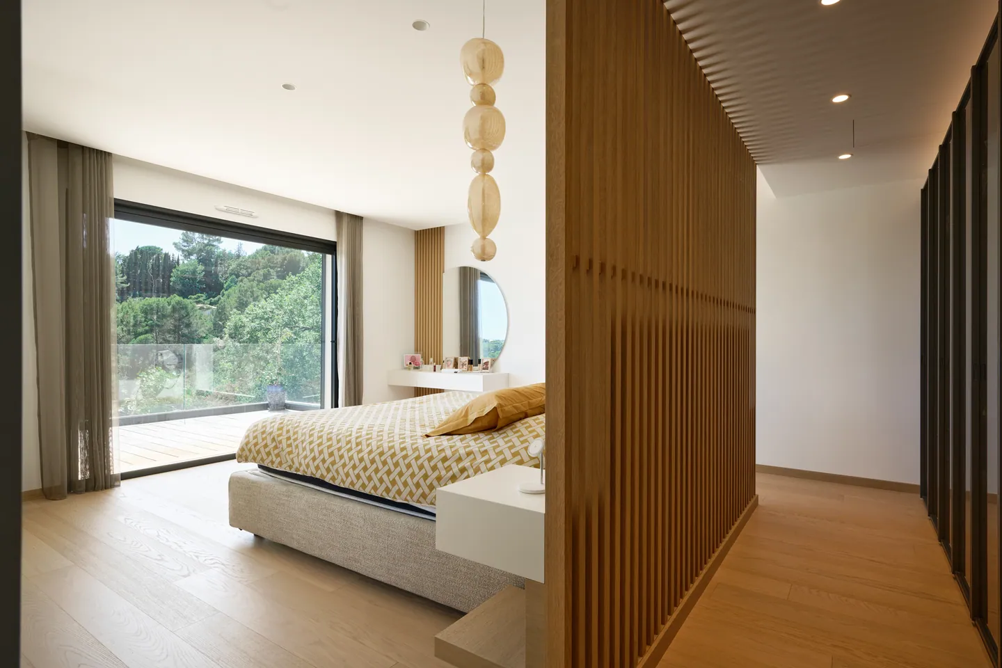 Chambre parentale, cloison à claire-voie en bois et baie ouverte sur un balcon arboré