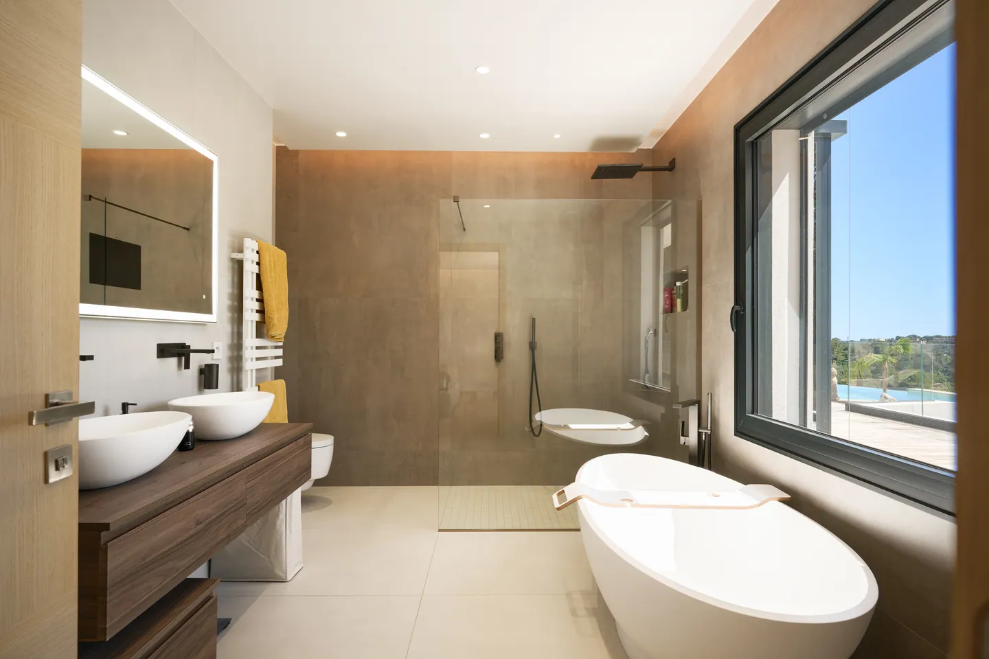 Salle de bains avec baignoire îlot, double vasque sur meuble bois et douche à l'italienne