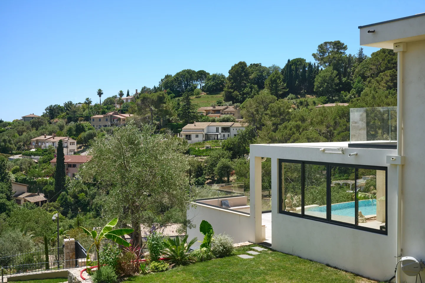 Jardin engazonné et massifs méditerranéens au pied de la villa, vue dégagée sur les collines
