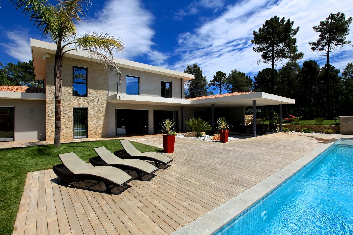 Villa à toitures-terrasses avec grand auvent, deck en bois, transats et piscine